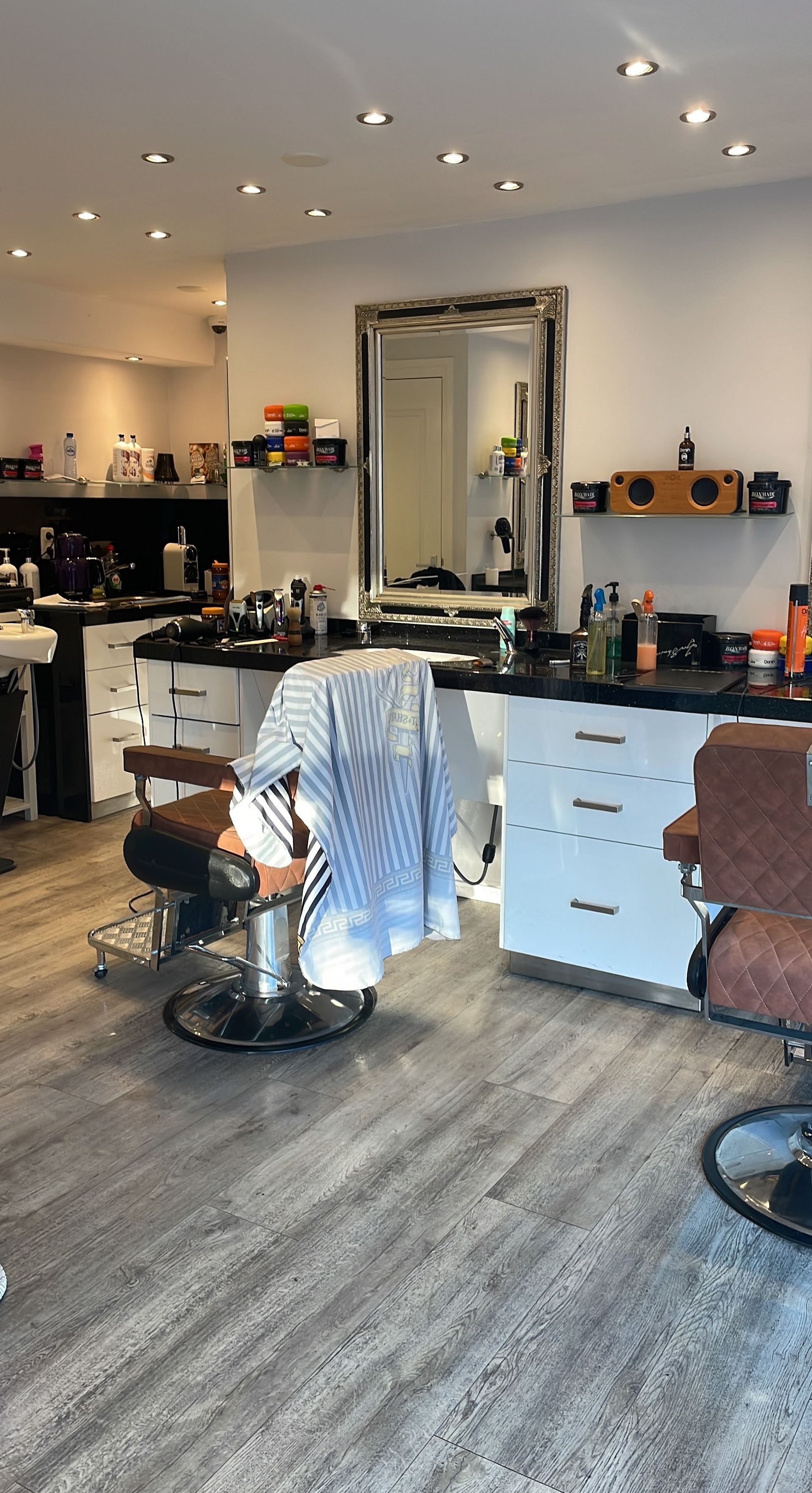De lege zaak: spiegels, zwarte werkbladen, cognac kappersstoelen en een grijze houten vloer